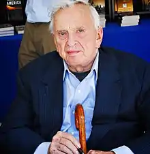 Gore Vidal in 2008 seated and holding a cane and pen.