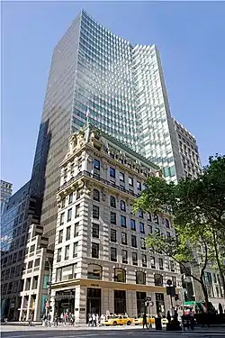 452 Fifth Avenue as seen from the corner of Fifth Avenue and 40th Street. In the front is the 10-story beige stone facade of the Knox Building, with a green mansard roof. Behind it is the glass facade of the 30-story HSBC Tower, which is colored blue and green on 40th Street to the right and dark-colored on Fifth Avenue to the left.