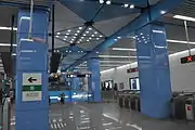 Station concourse with escalator and steps to platforms in the background