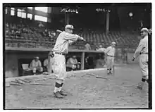 A man in an old-fashioned baseball uniform holds his bat above his shoulder, left-handed