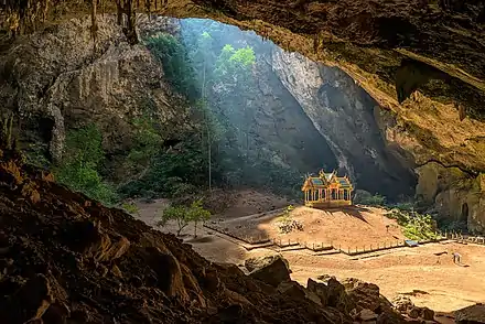 Photograph of a small royal pavilion basking in the sunlight shining through the roof of a large cavern