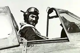 Man in flying helmet sitting in cockpit of military aircraft