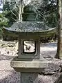 Stone lantern leading up to shrine framing a Nara Park deer