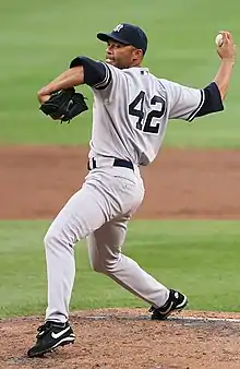 A man in a gray baseball uniform with navy under-sleeves and cap