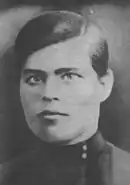 Portrait photograph of a young Nestor Makhno wearing a dark suit and neatly combed hair