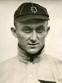 Portrait of a man wearing a high collar, held closed with a safety pin.