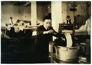 Edward McGurin, 14 years old, wringing curtains at Boutwell, Fairclough & Gold, 274 Summer Street, 1917; photo by Lewis Hine