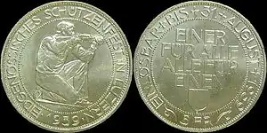 At left, the obverse of shooting thaler, showing a kneeling rifleman aiming to right, surrounded by the inscription EIDGENÖSSISCHES SCHÜTZENFEST IN LUZERN, with 1939 below. At right, the reverse, showing the words EINER FÜR ALLE, ALLE FÜR EINEN above the Lucerne coat of arms in the middle, with EINLÖSBAR BIS 31. AUGUST 1939 around the outer edge, and 5 FR at the bottom.