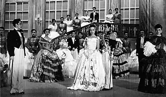 A historical photograph of a stage performance; all of the actors are women, some of whom are cross-dressing