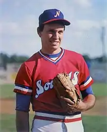 A man in a red baseball jersey, white pants, and blue cap