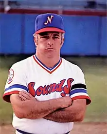 A man in a white baseball jersey and blue cap