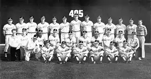 Thirty men on a baseball field; most are wearing light baseball uniforms and dark caps