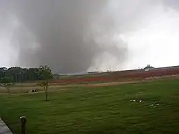 A tornado in the middle of the fields striking a motor plant.