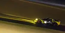 A yellow and black grand touring car in night time conditions