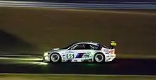 Side view of a white BMW M3 GT2 during night time driving conditions