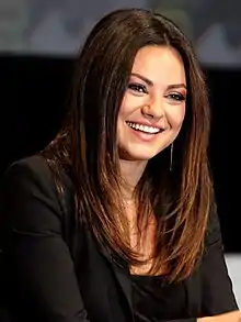 Mila Kunis smiles in a black dress