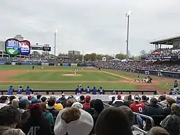 A baseball game being played on a green field involving a team in blue and a team in white