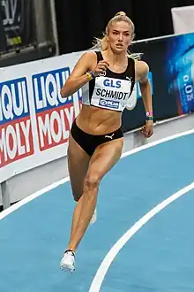Blonde  woman with a black top and black shorts running on indoor track