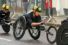 White woman dressed in black in a black wheelchair