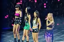 Blackpink standing onstage, facing leftwards