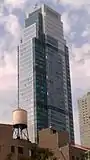 External shot of tower looking north, with one of its distinct wind turbines on the roof.