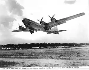 Black and white photo of a four engined aircraft taking off