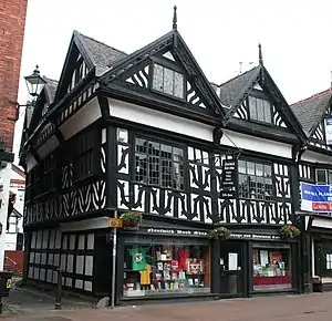 A black-and-white building in a corner position, with two gables to the front and three to the side.