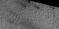 Close view of defrosting, as seen by HiRISE under HiWish program Gas and dark dust is probably being blown out of ground and then carried by winds toward the Northwest.  Arrow points to a possible spider formation.