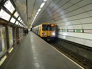 A Merseyrail train painted with a yellow front and grey sides. It is underground at Liverpool Central station.