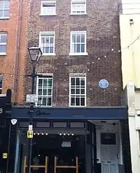 exterior of darked bricked house, with blue plaque on front wall