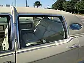 Closeup image of rear roofline of a 1977 Lincoln Continental Town Car, showing padded rear vinyl roof and opera windows.