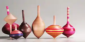 Seven wooden tops in a variety of shapes and colors