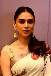 A woman with dark brown hair in a beige dress