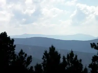 The more distant mountains are, the lighter and more blue they are.  This is called atmospheric perspective or aerial perspective.