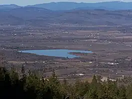 An image of a valley, taken from a hill looking down, showing a lake and houses