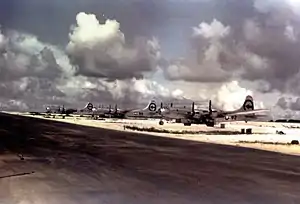 Three silver four-engine propellor aircraft parked next to a runway