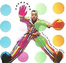 A man wearing a multi-colored striped suit has four colored circles in front of him: blue, magenta, green and orange. He has his left hand and foot on a magenta and blue circle respectively, and has his right hand and foot on the orange circles.