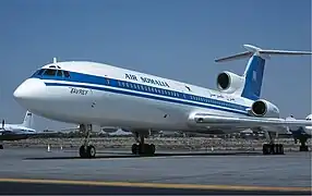 An Air Somalia Tupolev Tu-154, registration UR-85546, sitting idle on the taxiway at Sharjah International Airport. The livery is a blue stripe that spans the entire length of the plane, the line's location is just along the passenger windows. The tail fin is fully blue. Above the blue line is the text "Air Somalia", with a star next to it.