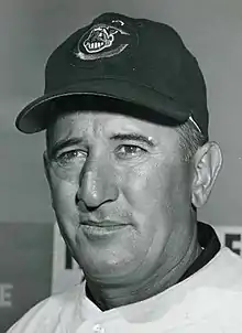 A man in a light baseball jersey and dark cap