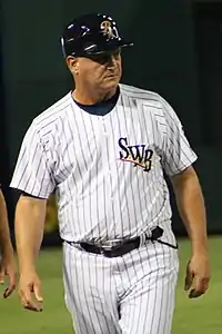 A man in a white baseball uniform with dark pinstripes