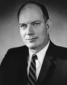 Black-and-white photo of a balding man in a suit and striped tie