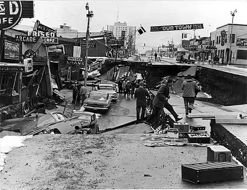 City street with one lane collapsed and several cars in a hole caused by the earthquake