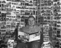 Albert K Bender sitting on chair reading magazine