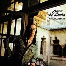 Man in denim jacket standing in a doorway leading into a hacienda courtyard