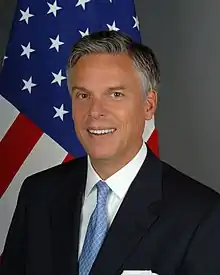 man in business suit, American flag in background