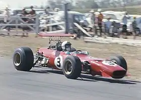 Single seat red racing car with open cockpit being track driven