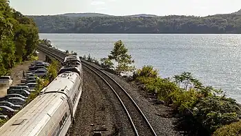 A passenger train on a riverside rail line