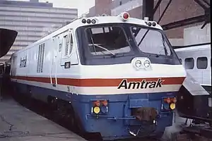 A white locomotive with black cab area, blue underside, and red stripe