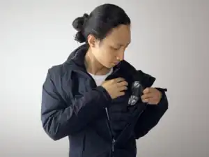 An actor shows and checks the bullet hit squib attached with duct tape to the inside of the jacket shell.