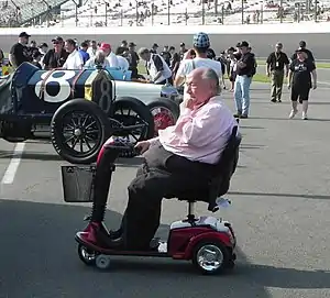 Andy Grantelli on a mobility scooter in the pit lane of a race track